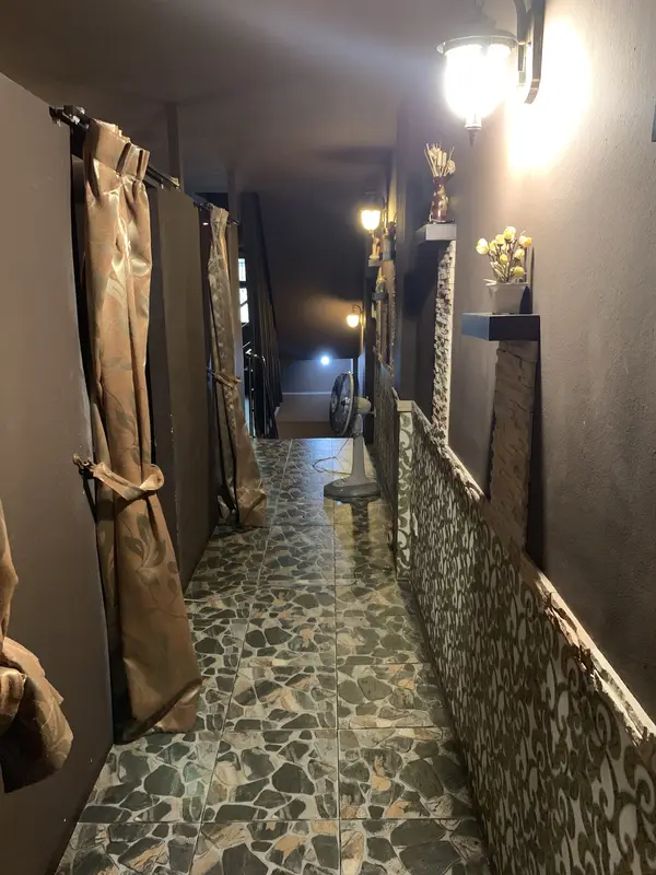 Upstairs corridor with curtained massage rooms, wall lamps and stone-pattern floor tiles