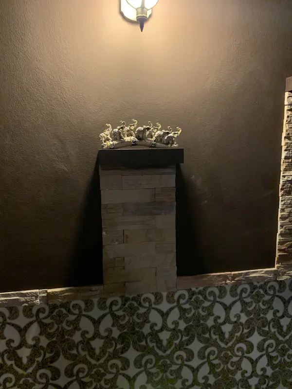 A row of carved elephant figures on a stone pillar under a wall lamp